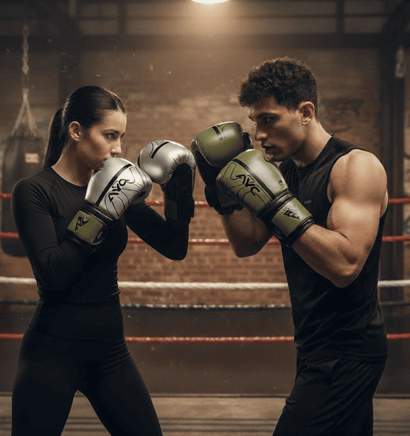 Man and woman sparring in a boxing gym wearing silver and army green AYC boxing gloves